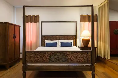 a bedroom with a canopy bed with blue pillows at Artisan's Antique House - Silom in Bangkok