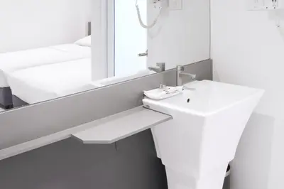 a white bathroom with a sink and a mirror at My Hotel Pratunam in Bangkok