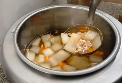 a pot of potatoes and carrots in a soup at My Hotel Pratunam in Bangkok