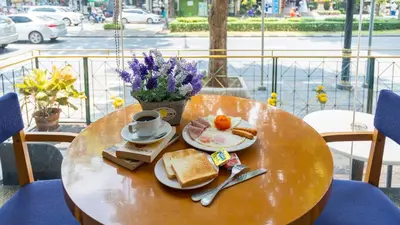 a table with a plate of food and a cup of coffee at For You Residence in Bangkok