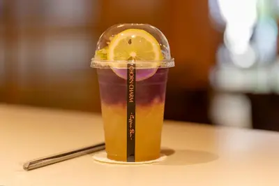 a drink in a plastic cup with a lemon slice in it at Myhotel Cmyk@Ratchada in Bangkok