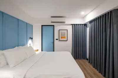 a bedroom with a white bed and blue curtains at Myhotel Cmyk@Ratchada in Bangkok