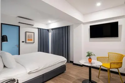 a bedroom with a bed and a table and a tv at Myhotel Cmyk@Ratchada in Bangkok