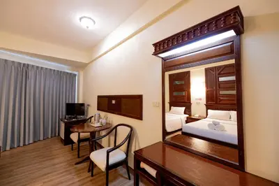 a hotel room with a bed and a desk and a mirror at MIDO Hotel in Bangkok