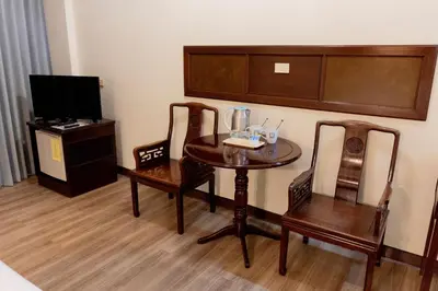 a room with a table and two chairs and a tv at MIDO Hotel in Bangkok