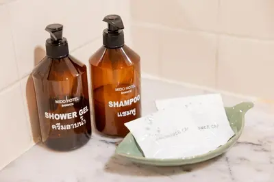 two shampoo bottles sitting on a counter with a plate at MIDO Hotel in Bangkok
