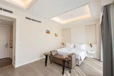 a white bedroom with a bed and a couch at Siam Tharadol in Bangkok