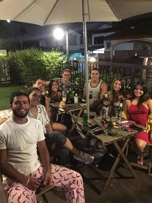 a group of people sitting at tables under an umbrella at Wayha Hostel Don Mueang Airport in Bangkok