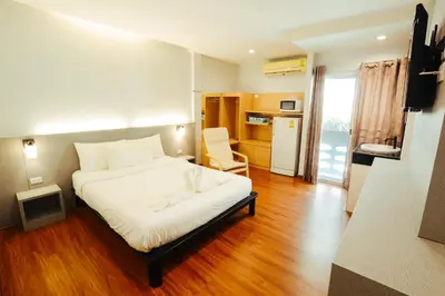 a bedroom with a white bed and a kitchen at Thaiphiphat house in Bangkok
