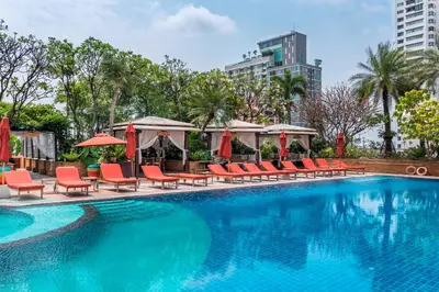 a swimming pool with red chairs and umbrellas at Sky Villas Apartments in Bangkok