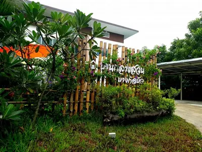 a wooden fence in front of a building with flowers at Baan Glangsuan Bang Kobua in Bang Chak