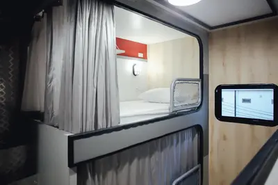 a small room with a bed and a window at Tales Khaosan (Cafe & Hostel) in Bangkok