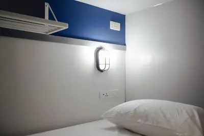 a bedroom with a bed with a blue accent wall at Tales Khaosan (Cafe & Hostel) in Bangkok