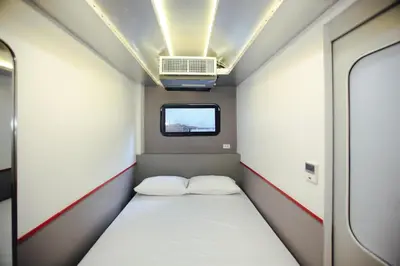a small room with a bed and a window at Tales Khaosan (Cafe & Hostel) in Bangkok