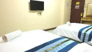two beds in a room with a tv on the wall at Goody Hotel in Bangkok