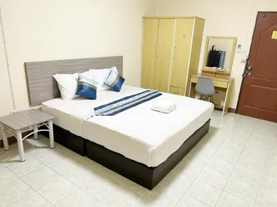 a bedroom with a large bed with a table and a chair at Goody Hotel in Bangkok