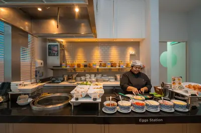 a man standing in a kitchen preparing food at Hyatt Place Bangkok Sukhumvit 24 in Bangkok