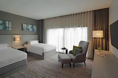 a hotel room with two beds and a chair at Hyatt Place Bangkok Sukhumvit 24 in Bangkok