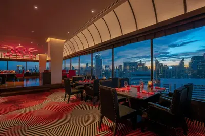 a restaurant with tables and chairs and a view of the city at The Landmark Bangkok in Bangkok