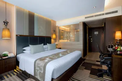 a hotel room with a large bed and a desk at The Landmark Bangkok in Bangkok