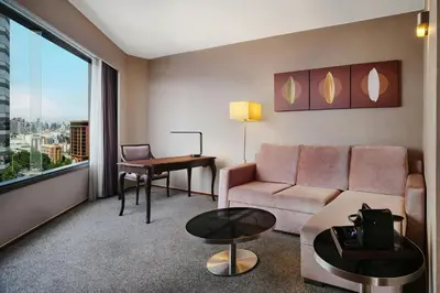 a living room with a couch and a table and a desk at Jubilee Prestige Hotel Ratchadapisek in Bangkok
