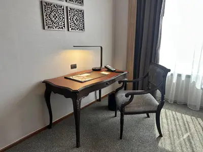 a desk in a room with a chair and a telephone at Jubilee Prestige Hotel Ratchadapisek in Bangkok