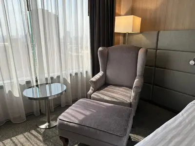 a room with a chair and a table in a hotel room at Jubilee Prestige Hotel Ratchadapisek in Bangkok