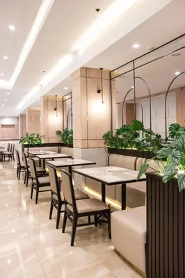 a restaurant with tables and chairs and plants at Twin Towers Hotel in Bangkok