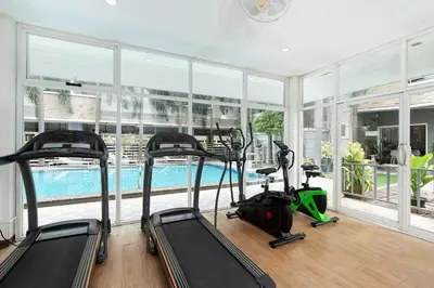 a gym with three treadmills and a swimming pool at P-Park Suvarnabhumi in Bangkok