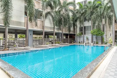 a swimming pool in front of a building with palm trees at P-Park Suvarnabhumi in Bangkok