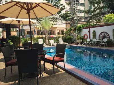a table with an umbrella next to a swimming pool at Stable Lodge - SHA Certified in Bangkok