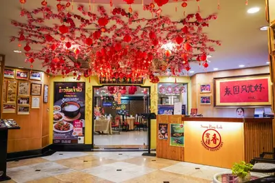 a restaurant with red flowers hanging from the ceiling at Grand China Bangkok in Bangkok
