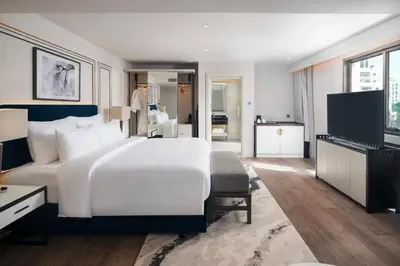 a bedroom with a large white bed and a television at Radisson Hotel Chateau de Bangkok in Bangkok