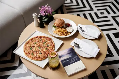 a table with a pizza and a sandwich and french fries at Radisson Hotel Chateau de Bangkok in Bangkok