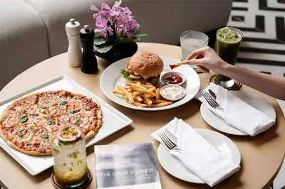 a table with a pizza and a hamburger and french fries at Radisson Hotel Chateau de Bangkok in Bangkok