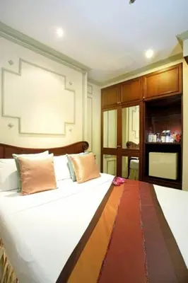 a bedroom with a large white bed with brown pillows at Majestic Suites Hotel in Bangkok