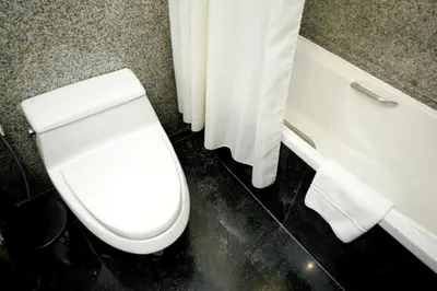 a bathroom with a white toilet and a bath tub at Majestic Suites Hotel in Bangkok