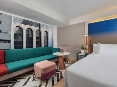 a bedroom with a bed and a couch and a table at Pipa Hotel Bangkok Sukhumvit 11 in Bangkok