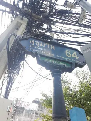 a blue street sign on a pole with wires at Baan mek mok in Bangkok