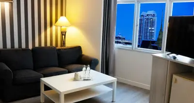 a living room with a couch and a table and a window at Trang Hotel Bangkok - SHA Plus in Bangkok