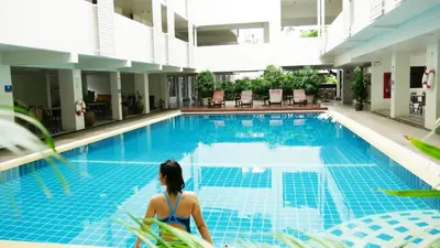 a woman sitting on a chair in front of a swimming pool at Trang Hotel Bangkok - SHA Plus in Bangkok