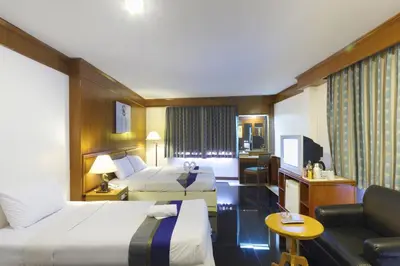 a hotel room with two beds and a couch at Silom Avenue Inn in Bangkok