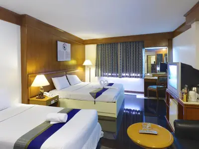 a hotel room with two beds and a desk at Silom Avenue Inn in Bangkok