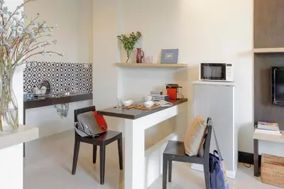 a kitchen with a counter with chairs and a microwave at @Home Residence in Bangkok
