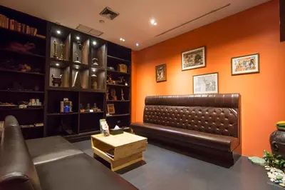 a leather couch in a room with an orange wall at Buddy Lodge, Khaosan Road in Bangkok