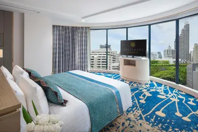 a hotel room with a bed and a tv on a balcony at Solitaire Bangkok Sukhumvit 11 in Bangkok