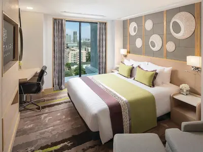 a hotel room with a large bed and a desk at Solitaire Bangkok Sukhumvit 11 in Bangkok