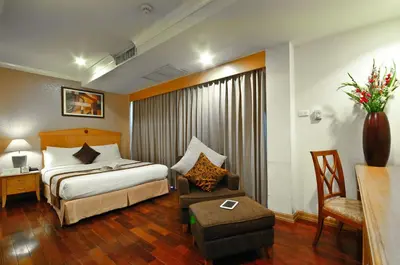 a hotel room with a bed and a chair at Admiral Suites Bangkok in Bangkok