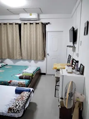 a room with two beds and a television in it at Danee Hostel in Bangkok