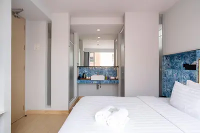 a bedroom with a white bed with towels on it at Metz Pratunam in Bangkok